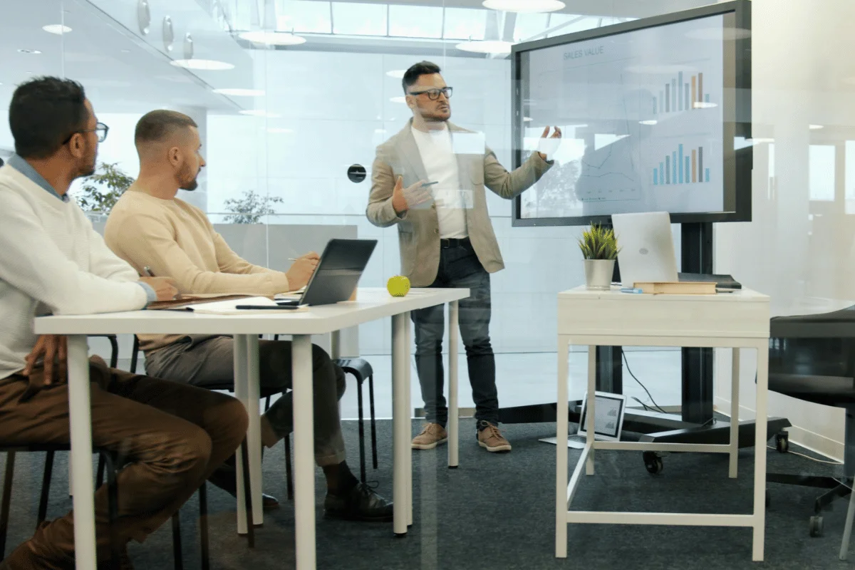 A man presents data on a screen to three colleagues in an office.