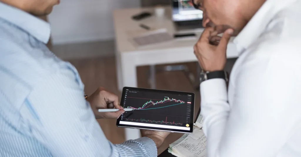 Two professionals analyzing stock market data analytics ROI on tablet screen in modern office setting.