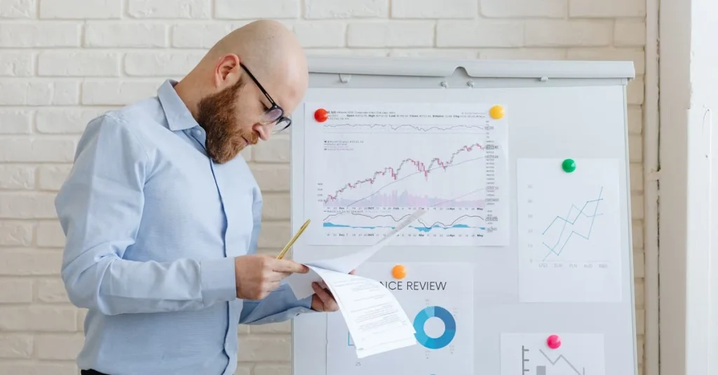 Man reviewing business intelligence dashboard with charts and graphs on whiteboard against brick wall.